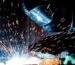 Person in Welding Mask While Welding a Metal Bar